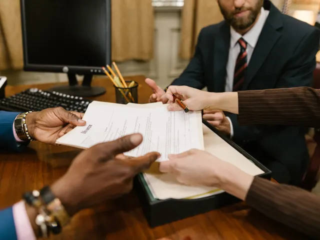 Manos revisando y firmando documentos en una reunión